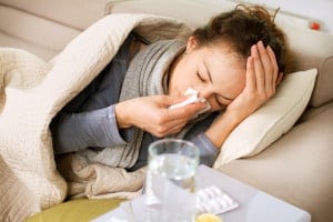 Woman on Couch with the flu Blowing Her Nose